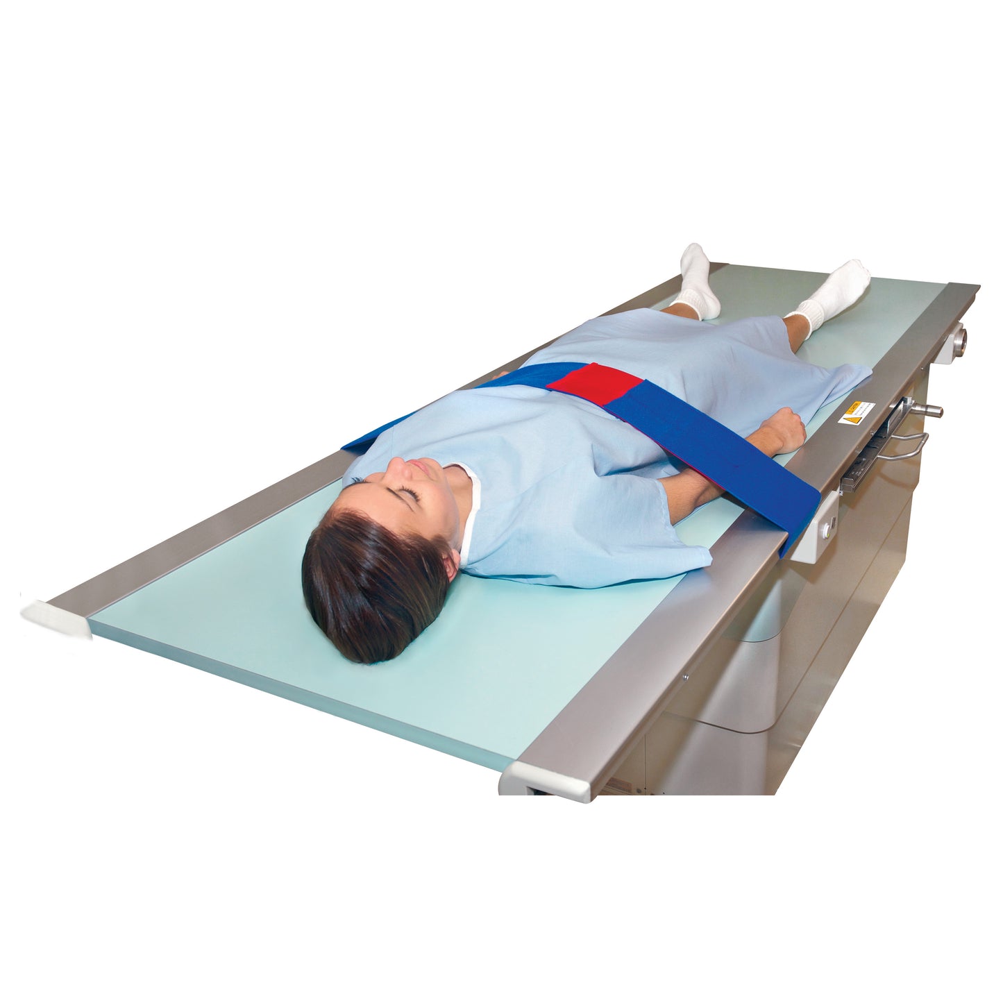 A person lies on a table secured with the AliMed Universal Strap, One-Piece, One Closure, No Side Rail in red and blue.