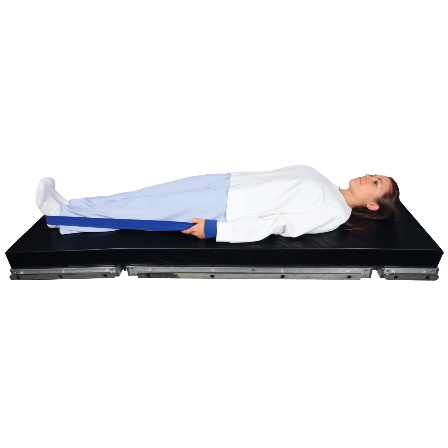 A person lies on a black mat using the AliMed Auto Traction Strap, which is secured around their foot and gripped in their hand.