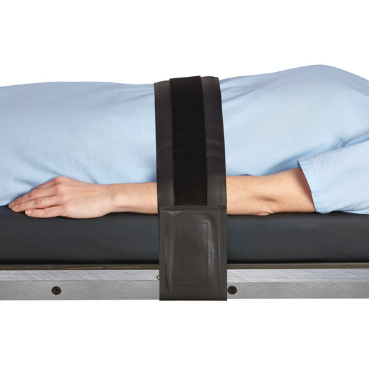 A person wearing a light blue garment lies on a table, with arms secured by an AliMed AliGel Surgical Table Strap across the torso.