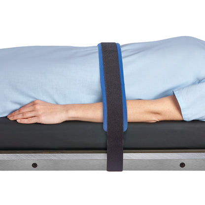 A person on a table secured with an AliMed Disposable Surgical Strap, which is black with blue edges.